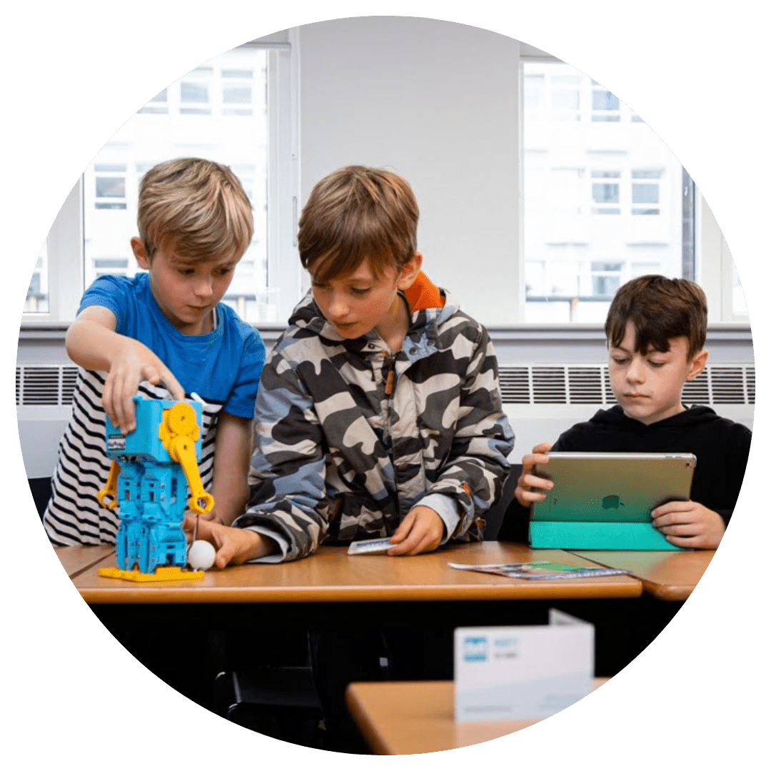 Three boys programming Marty the robot to kick a ball